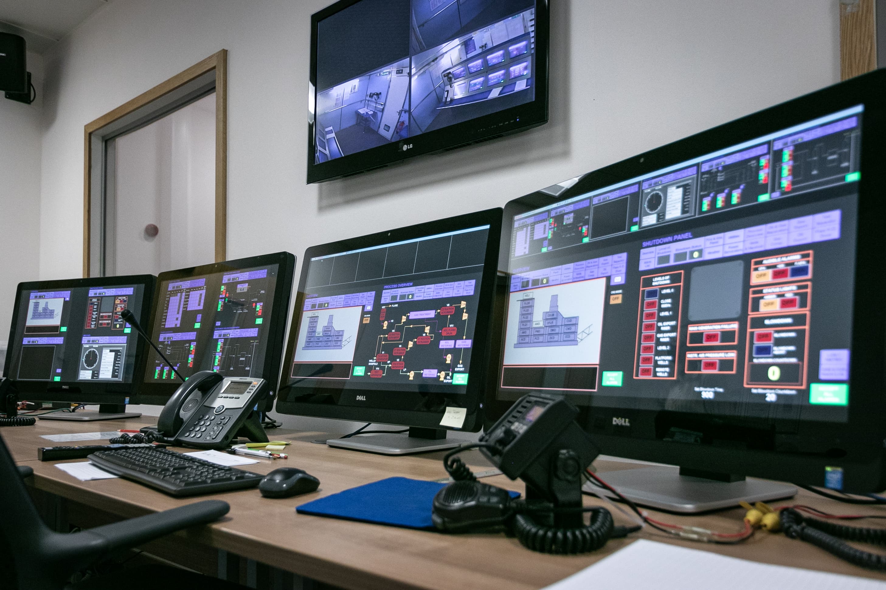 A control room with multiple monitors displaying complex systems and real-time data, showcasing the high-tech operations and monitoring required for industrial safety and performance management.